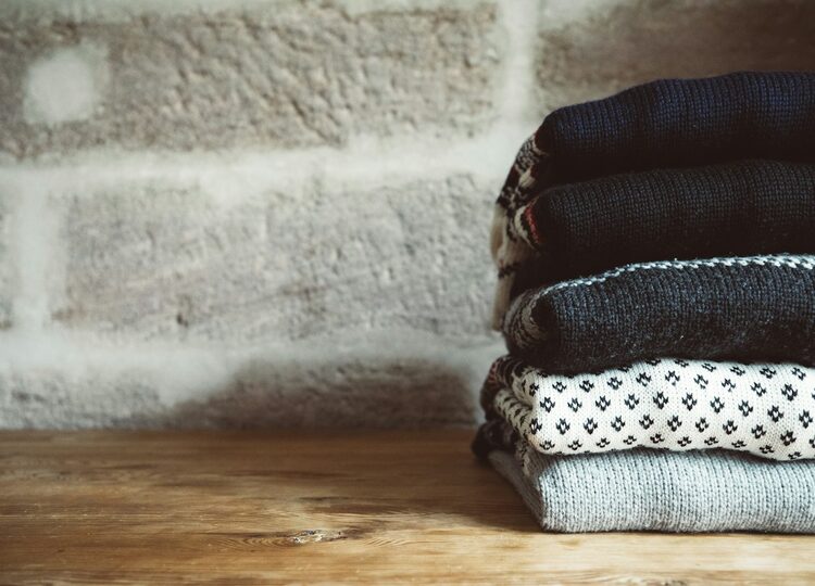 Stack of knitted sweaters in mixed gauges